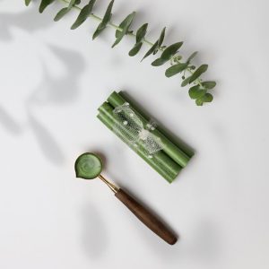 موم قلمی به رنگ سبز در کنار قاشقک فلزی مخصوص ذوب