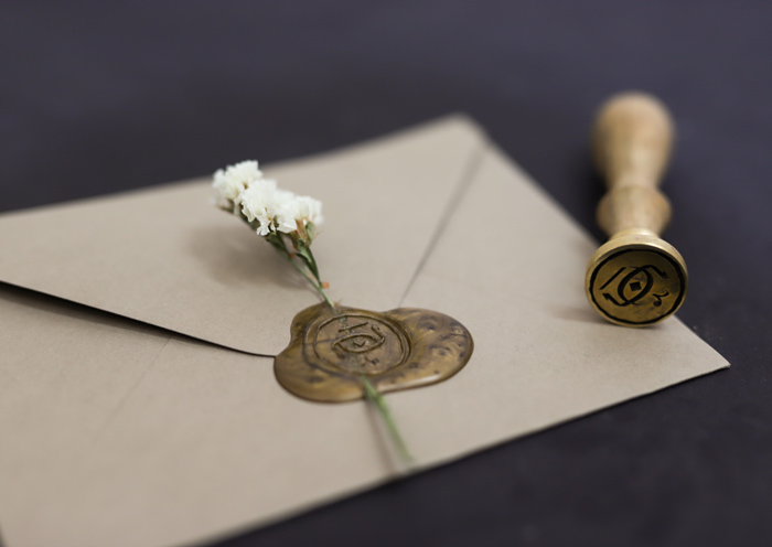 مهربرنجی مهروموم با لوگوی نشان و پاکت نامه مهروموم شده با موم طلایی رنگ و گل خشک